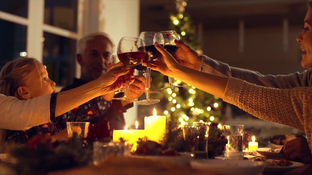 Family toasting wine at christmas dinner. Family enjoying christmas dinner together at home, with focus on hands and wine glasses.