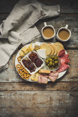 dish with cheese and cheese assortment - cheese, salami, crackers, olives, dried tomatoes and plums and other
