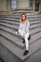 Stylish curly blonde model girl wear on white with cup of coffee posing on stairs outdoor.