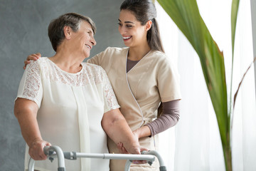 Smiling daughter supporting elderly mother