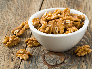 white cups with walnut, bowls with handful of nuts  on grey wooden background. great depth of field, side view