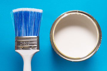 Brush and paint can on blue background