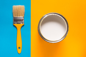 Brush and paint can on blue yellow background