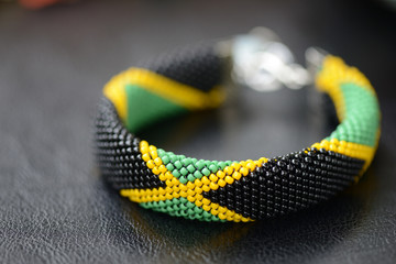 Bead crochet bracelet in the colors of the flag of Jamaica on a dark background