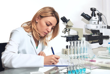 Young female scientist or tech writes down progress report