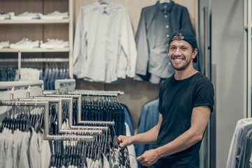 Young man choosing clothes in shopping mall