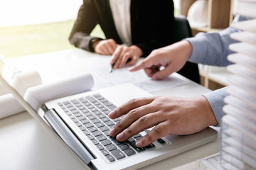 Engineering or Creative architect in construction project, Engineers hands working on construction blueprint and building model at a workplace in office, Building and architecture concept