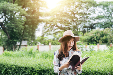 Attractive asian woman reading a book and relaxing at the park