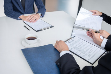 Interviewer or Board reading a resume during a job interview, Employer interviewing a young male job seeker for recruitment talking in modern office, employment and recruitment concept