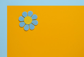 Blue flower made of felt on a blue and orange background. Space for text