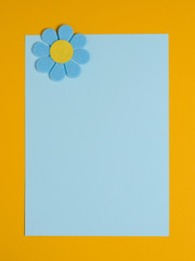 Blue flower made of felt on a blue and orange background. Space for text