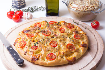 Fresh bread focaccio with tomatoes, cheese brynza, garlic and thyme. Traditional Italian bread. Selective focus, close-up.