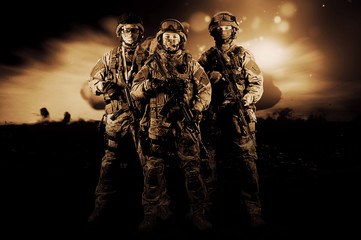 Three soldiers in uniform with a weapon in their hands are looking menacingly.