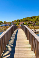 Fototapeta na wymiar Holzbrücke über einen Wasserzulauf direkt zum Mittelmeer bei der kleinen französischen Ortschaft Gruissan in Südfrankreich