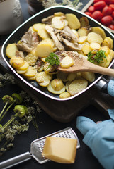 fried potatoes with mushrooms and cheese, in a frying pan, on a black background