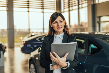 Portrait of attractive woman car dealer in showroom.