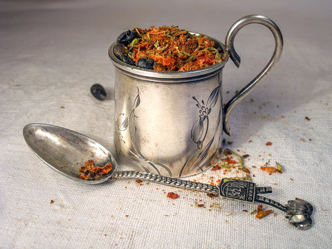 dry spices in vintage silver cup and spoon on flax background