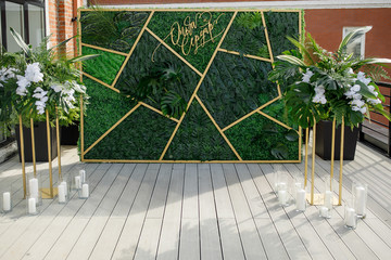 Wall with green and golden decor stands before chairs in the garden