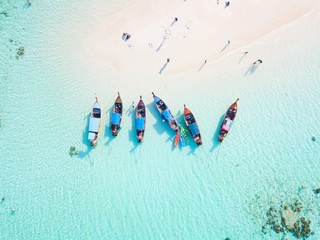Top view or aerial view of longtail boats on crystal clear water along the sand beach in Phuket Thailand - obrazy, fototapety, plakaty