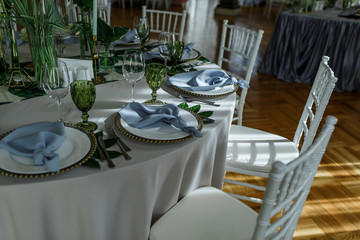 Grey serviette lies on white plate on green tablecloth