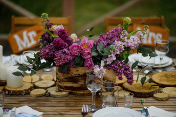 Bouquet of violet lilac and tulips stands on the wooden decor on the table