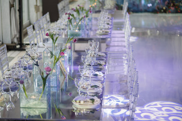 Mirror dinner table decorated with pink flowers and served with white plates