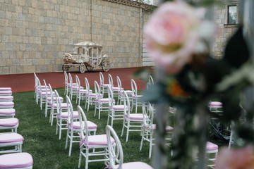 White chairs with pink seats stand on the green lawn