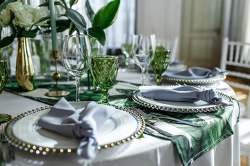 Grey serviette lies on white plate on green tablecloth