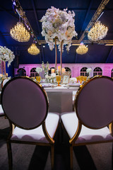 Look from behind round chairs at dinner table decorated with large bouquet of roses