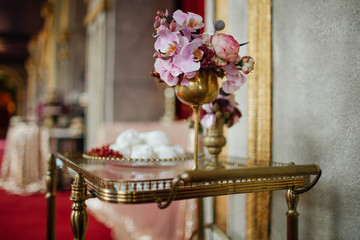 Golden goblet with pink flowers stands on a little table