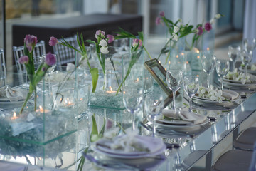 Mirror dinner table decorated with pink flowers and served with white plates