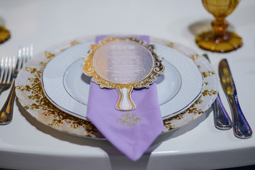 Violet napkin lies on golden plate on a dinner table
