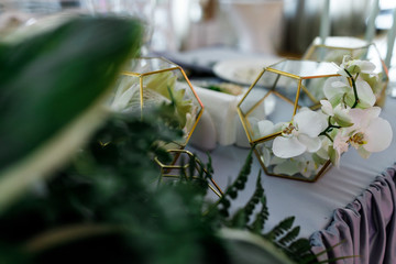 Golden cubes with white flowers stand on grey table for newlyweds