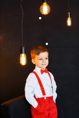 Little boy in white shirt, red pants and bow-tie having fun on his birthday and playing in big...