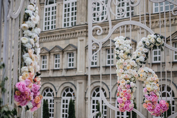 White steel gates with newlyweds' initials made of white and pink flowers