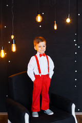 Little boy in white shirt, red pants and bow-tie having fun on his birthday and playing in big...