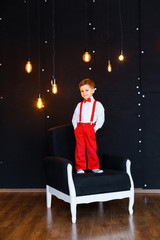 Little boy in white shirt, red pants and bow-tie having fun on his birthday and playing in big...