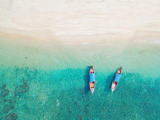 Top view or aerial view of longtail boats on floating on emerald clear water along the sand beach...