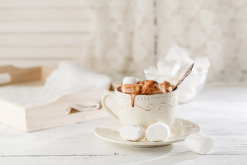 Mug of hot chocolate with marshmallows, on light wooden background
