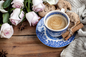 coffee in a vintage cup, on a wooden background and a bouquet of white roses