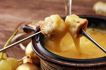 Gourmet Swiss fondue dinner on a winter evening with assorted cheeses on a board alongside a heated...