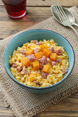 risotto italiano con zucca gialla e salsiccia su sfondo rustico