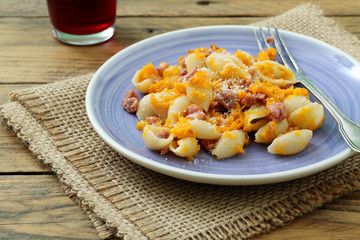 pasta italiana con zucca gialla e salsiccia su sfondo rustico