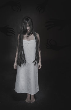 Mystical ghost woman with long black hair and shadow hands on dark