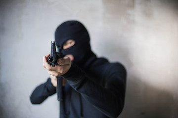Terrorist or gunman wearing a mask and holding a gun ready to fire