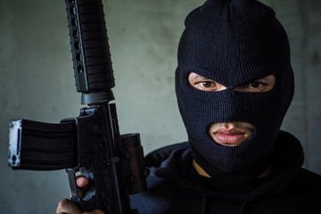 Terrorist or gunman wearing a mask and holding a gun ready to fire