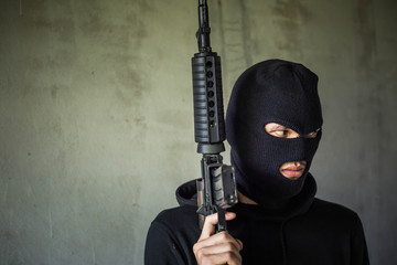 Terrorist or gunman wearing a mask and holding a gun ready to fire