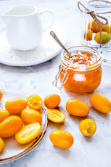 kumquat on plate and jam in jar at gray background