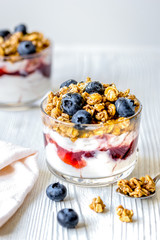 Morning granola with yogurt and berries on white kitchen backgro