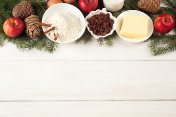 Baking ingredients on white table. eggs, butter, spice, apples, raisins, vanilla and cinnamon sticks, white flour and xmas tree on white wooden table background. Top view, copy space